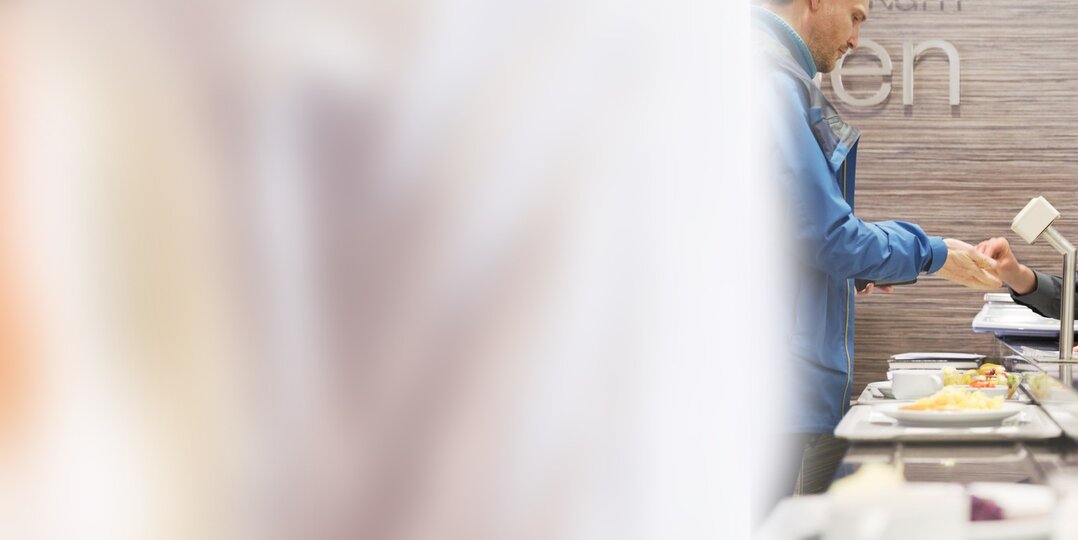Employé du service Dussmann à la caisse dans la zone de restauration - Gestion efficace de la cafétéria