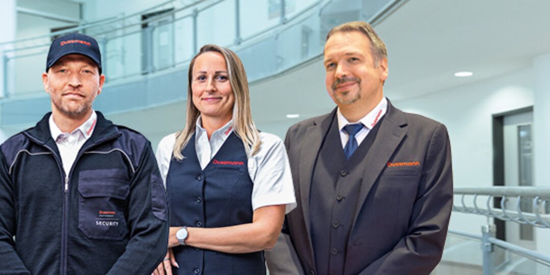 Photo de groupe de trois employés souriants de Dussmann, issus du service de sécurité
