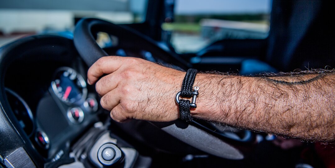 Mains d'un chauffeur livreur tenant fermement le volant d'un camion