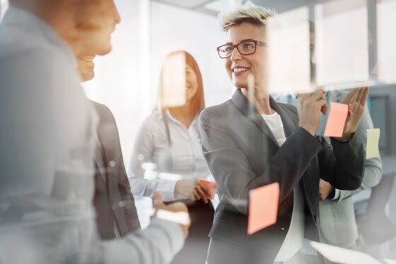 Femme en réunion collant des post-it avec le sourire – Une collaboration créative et dynamique pour des idées innovantes