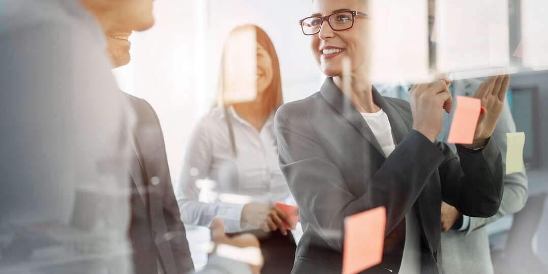 Femme en réunion collant des post-it avec le sourire – Une collaboration créative et dynamique pour des idées innovantes