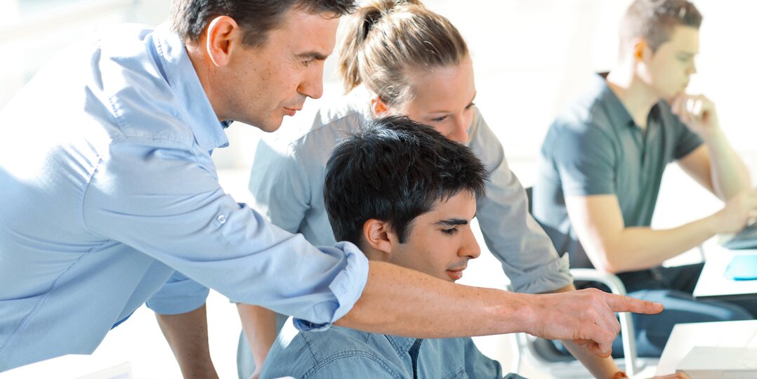 Homme et femme collaborant avec un jeune homme sur un ordinateur
