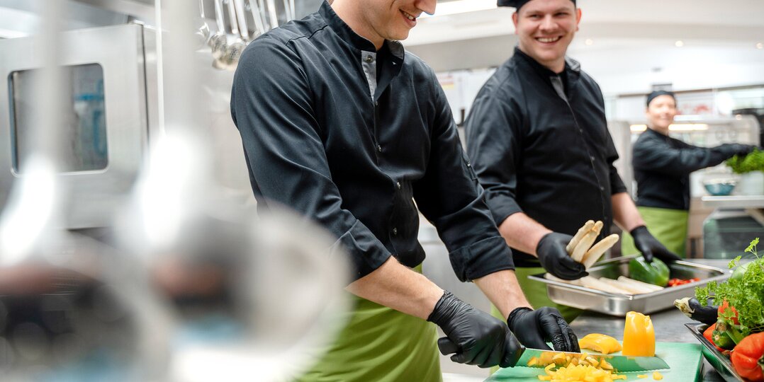 Deux cuisiniers coupant des légumes dans une cuisine professionnelle