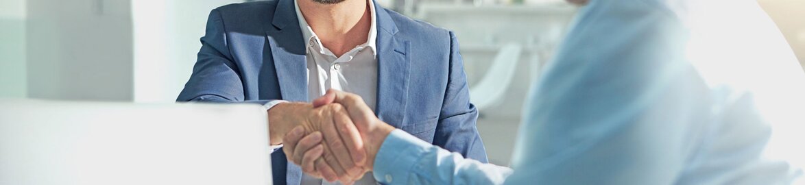 Deux hommes se serrant la main dans un bureau professionnel – Une collaboration réussie dans le secteur tertiaire