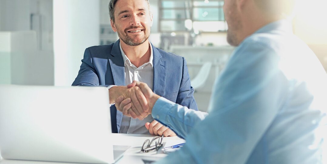 Deux hommes se serrant la main dans un bureau professionnel – Une collaboration réussie dans le secteur tertiaire